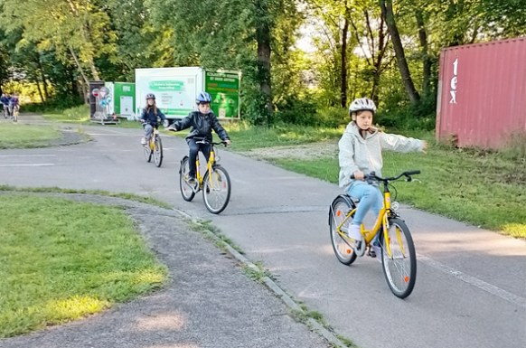 Kinder_auf_Fahrraedern_mit_Helm_geben_Handzeichen_in_der_Verkehrsschule